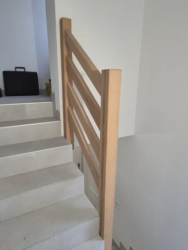 Garde-corps en bois le long d’un escalier carrelé, vu du bas